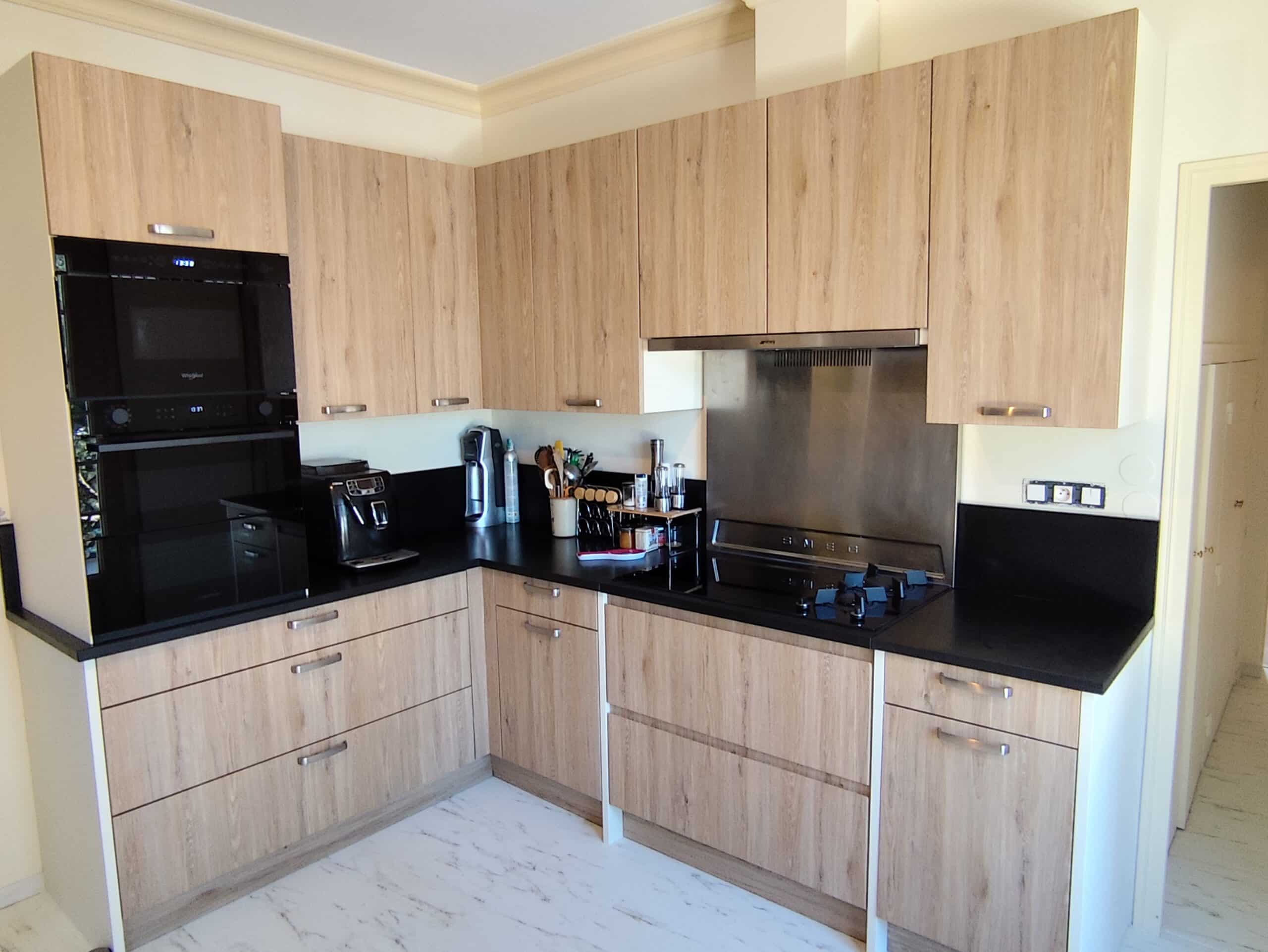 Cuisine moderne équipée en bois clair et noir avec plaque de cuisson SMEG et sol effet marbre blanc.